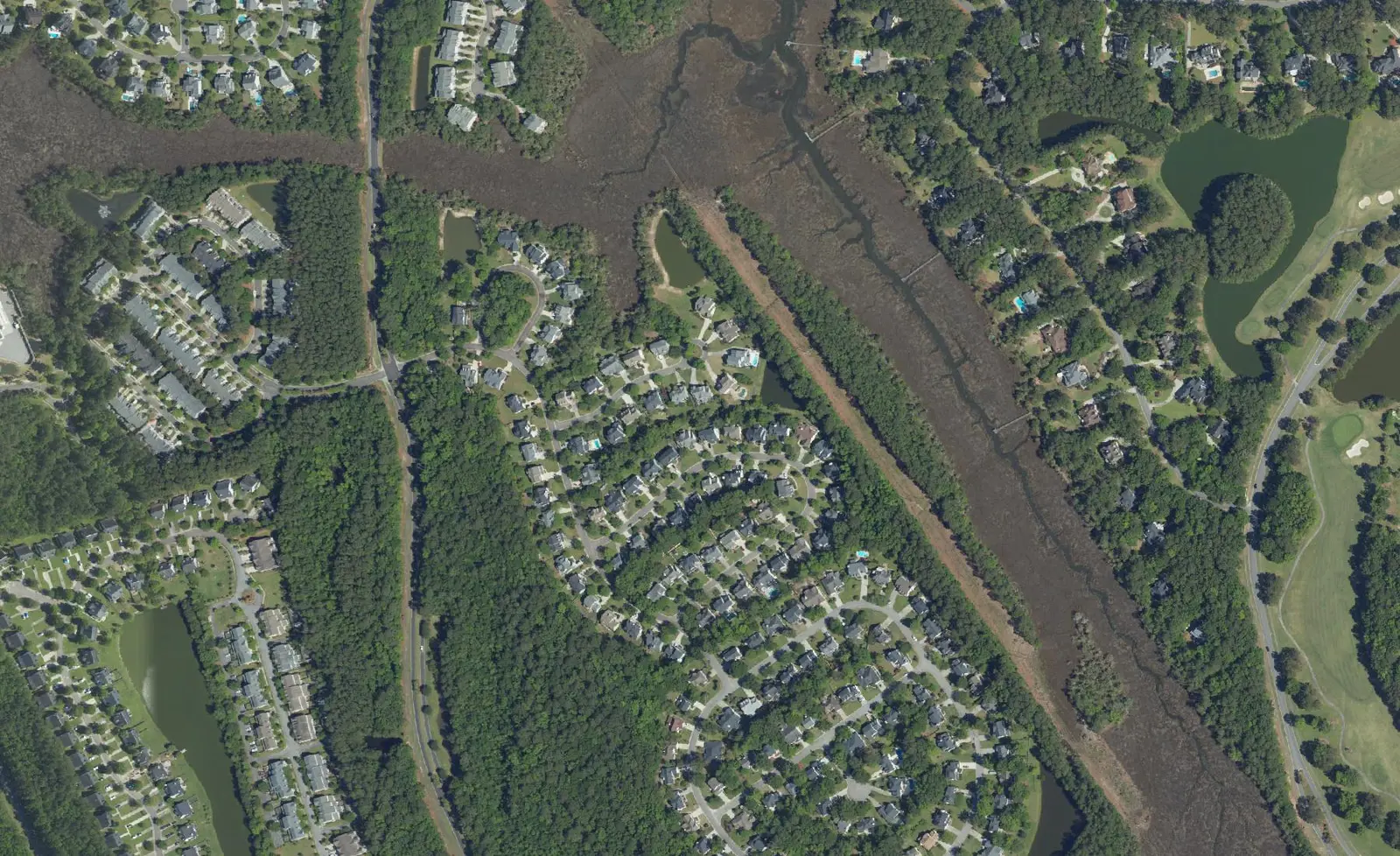 Aerial view of Dunes West in Mount Pleasant, with homes, a marsh creek and golf course fairways.